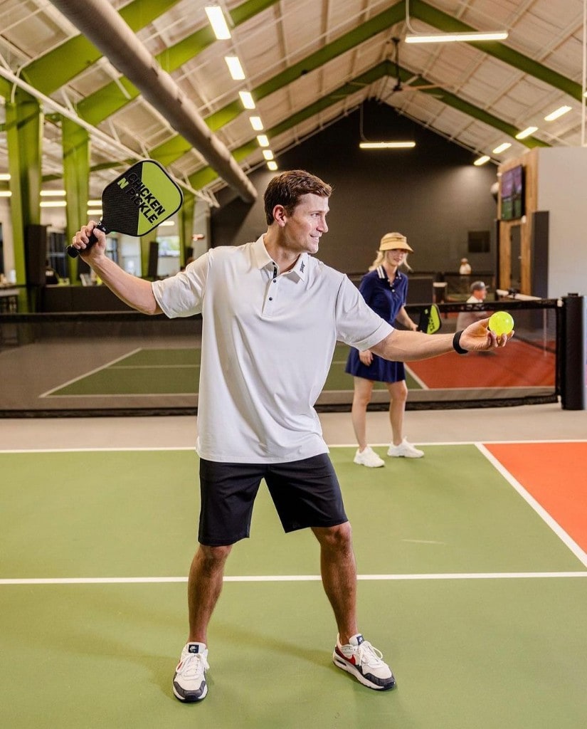 A player ready to serve during a coaching session on a premium indoor pickleball court